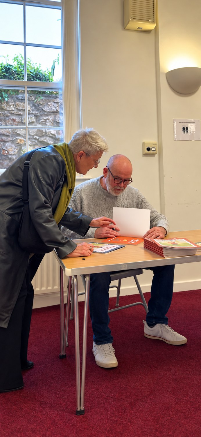 Paul signing a children's book while speaking with a reader